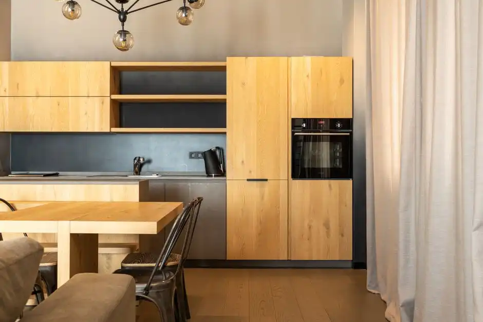 Cozinha de apartamento com armários de madeira clara e bancada